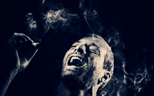 man smoking a cigar and laughing like a villain in the dark